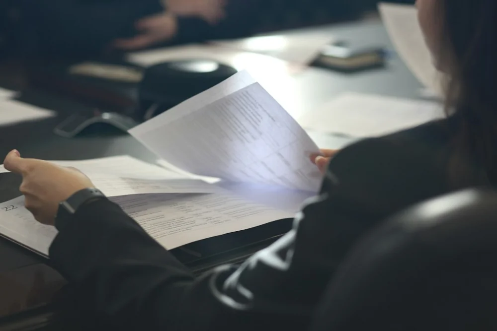 Pessoa analisando documento em mesa de escritório, imagem editorial sobre rescisão trabalhista e conferência de verbas